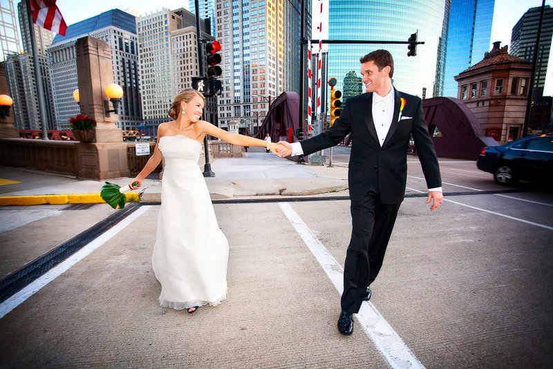 Bride and groom walking hand in hand  in downtown Chicago with sky scrappers in the backgrounds.