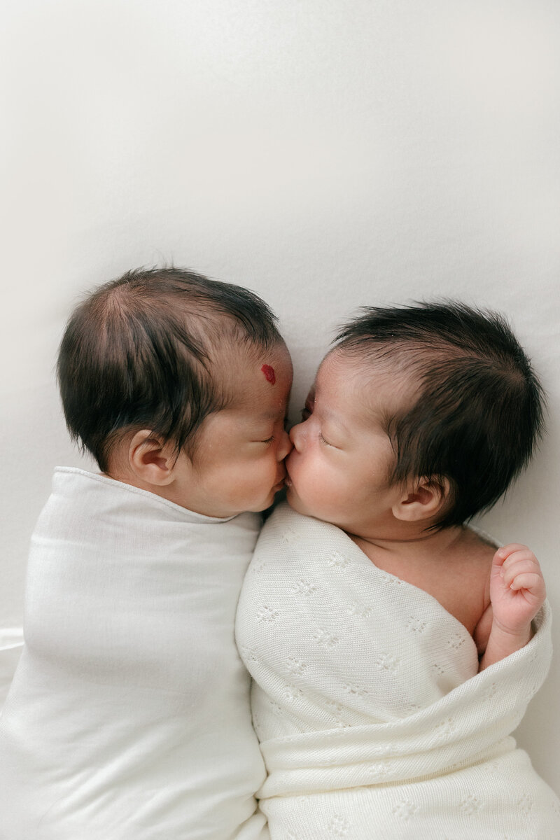 Newborn twins snuggling up close with all white background in all white studio by NJ photographer