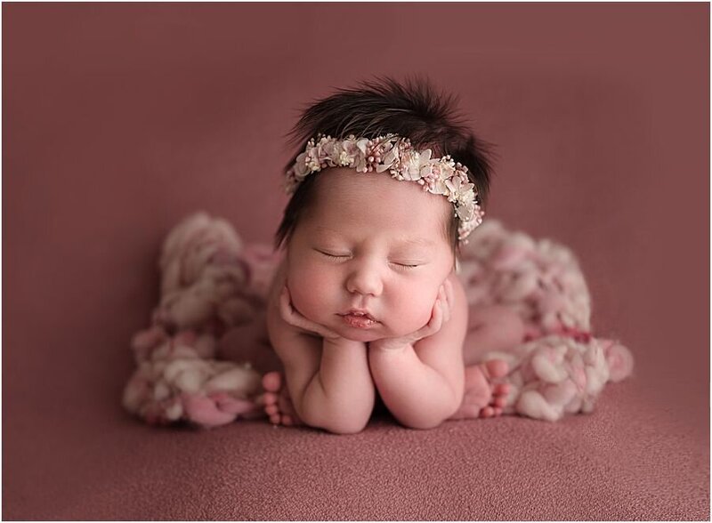 newborn baby girl in the froggy posed, wearing a pink flower crown