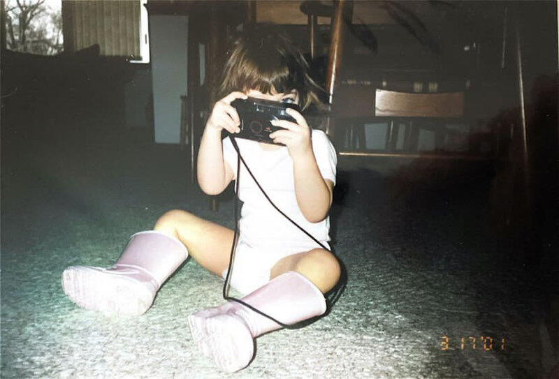 Little girl sitting on the floor, holding a camera
