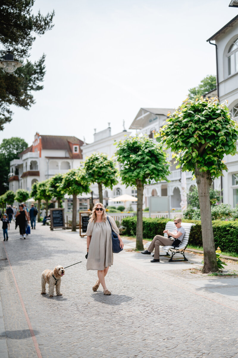 Frau spaziert mit Hund über die Binzer Promenade.