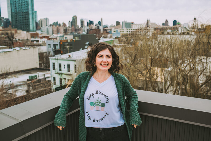 Maria, host of Bloom & Grow Radio, stands on her rooftop in front of NYC skyline