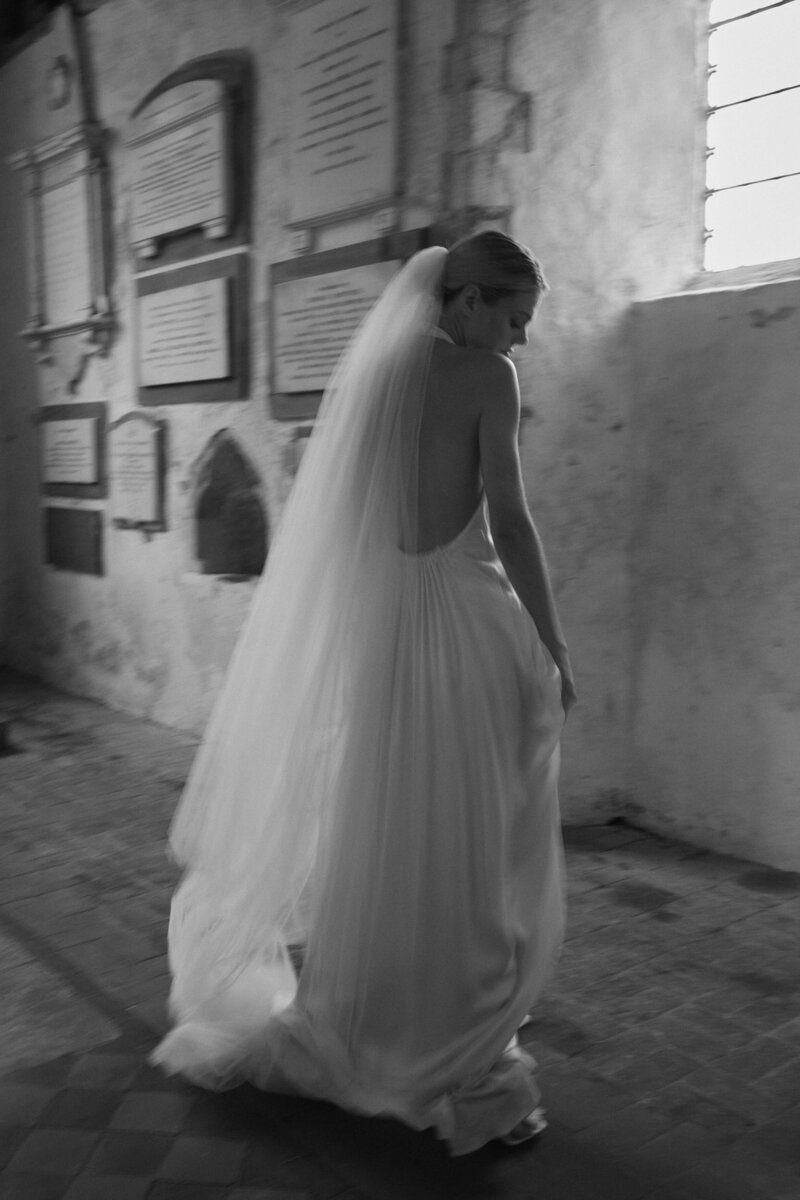 Bride wearing wedding long wedding veil and backless, sleeveless dress in church wedding