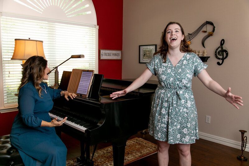 Amy Canchola teaches a young student singing as the student is singing next to the piano