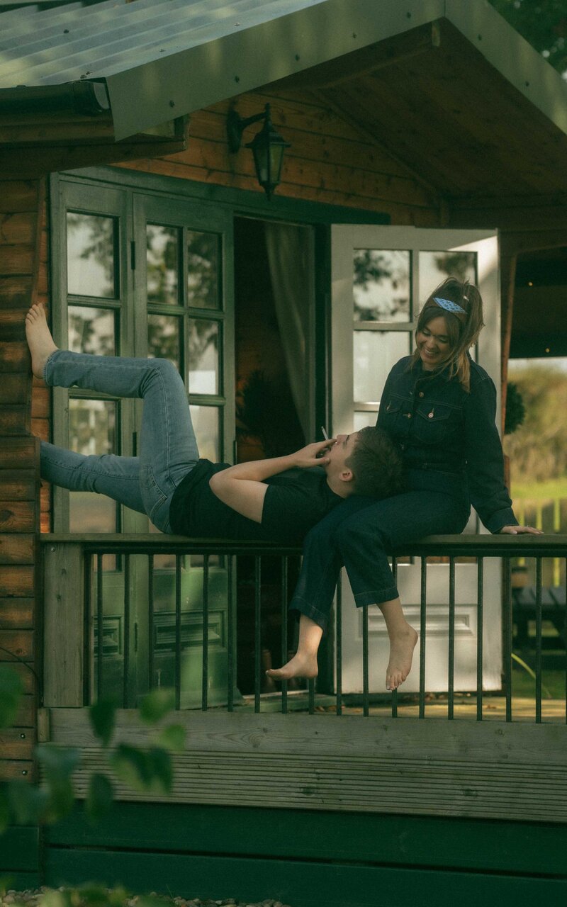 Relaxed couple sitting on the porch, enjoying a peaceful moment together with a cozy, intimate vibe, surrounded by a serene atmosphere