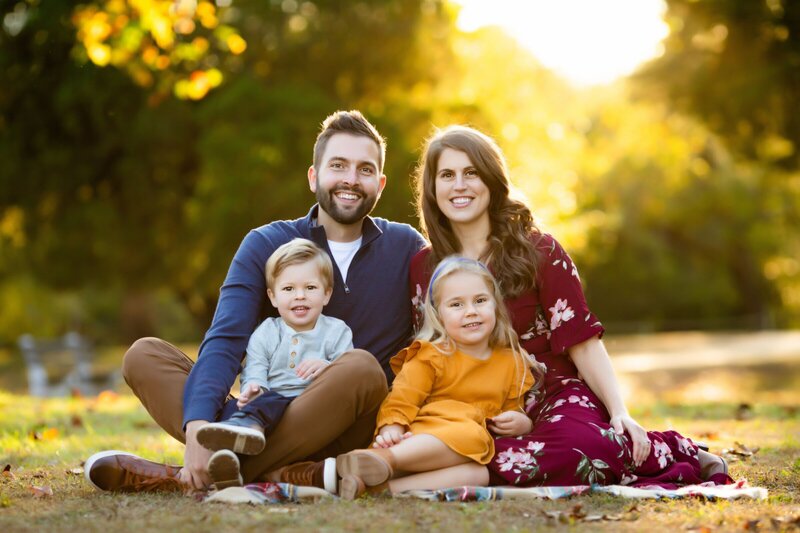 Family sitting in a park smiling at new jersey family photographer