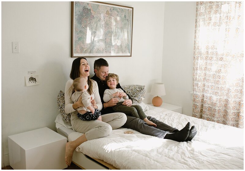 Mother and father sitting on bed with toddler and baby for sweet at home family session in Austin by Amber Vickery Photography