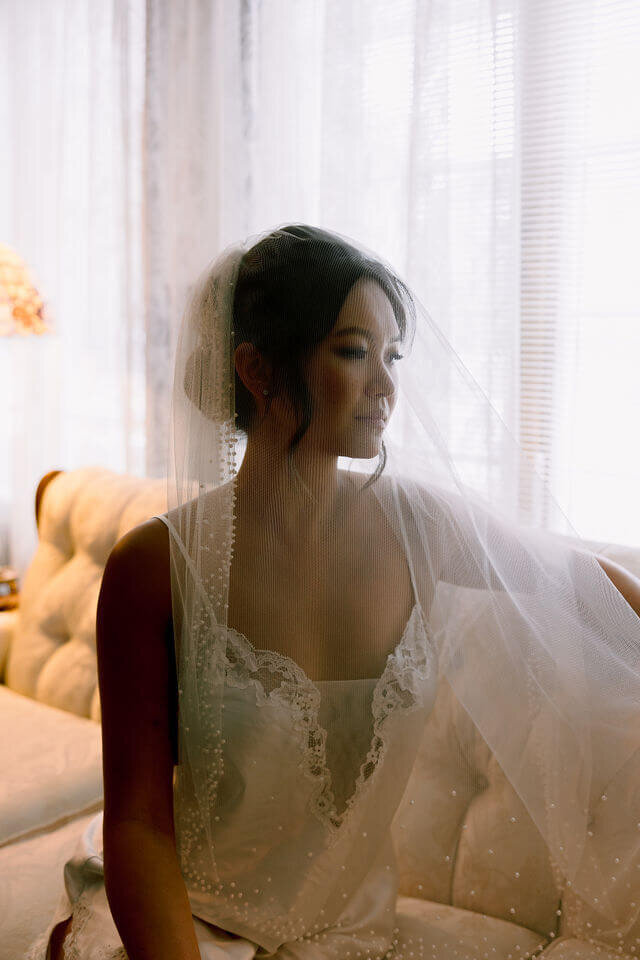 A beautiful bride wearing a white gown is seated on a couch, looking serene and elegant in Washington DC