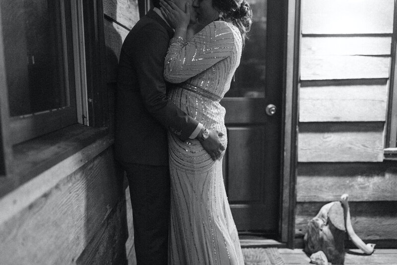 black and white image of couple kissing against a wall on their wedding day