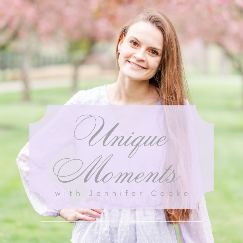 Lady wearing a lavender blouse smiles at the camera in a field of pink trees