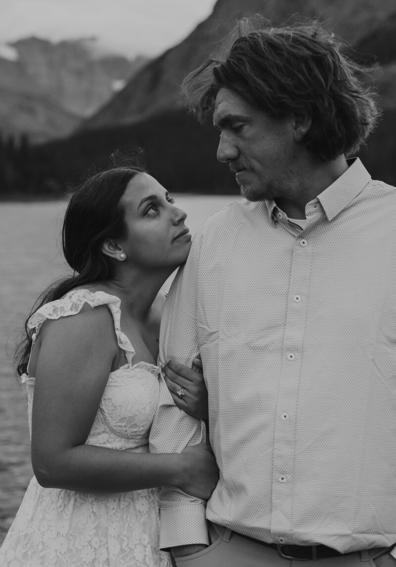 A black and white photo of a couple embracing and looking at each other during their elopement in Glacier National Park.