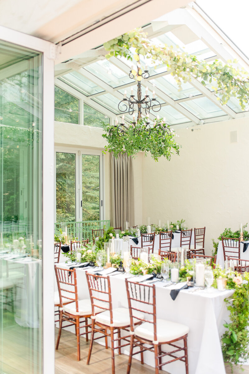 White and black outdoor wedding reception with lots of greenery.