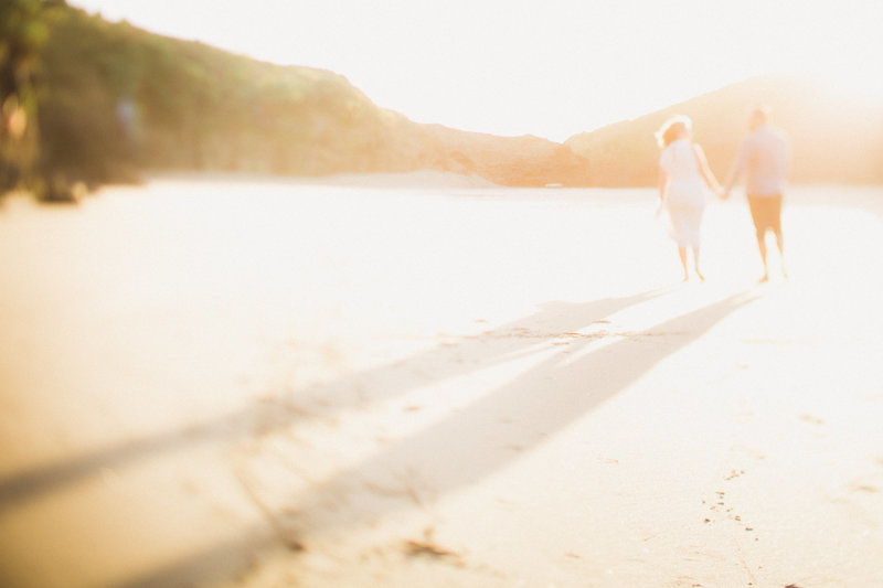 an out of focus photo of a couple walking on Piha Beach, New Zealand