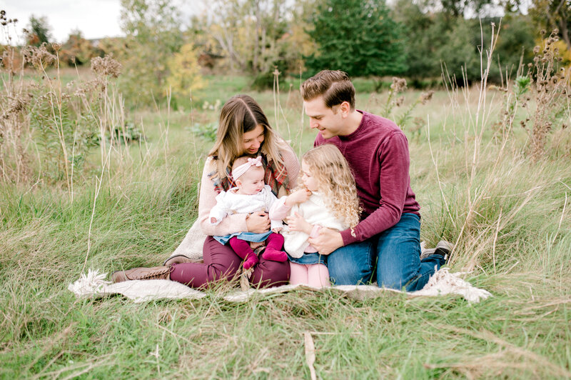 Kristine Marie with her family in a fields while sitting on a blanket