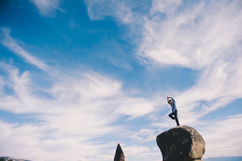 lake Tahoe family portrait of a boy standing tall on a boulder with big blue sky and clouds