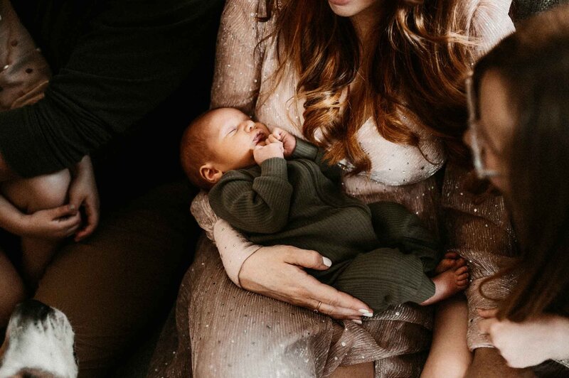 Mom-holding-newborn-on-couch-lifestyle-in-home-session-Missouri