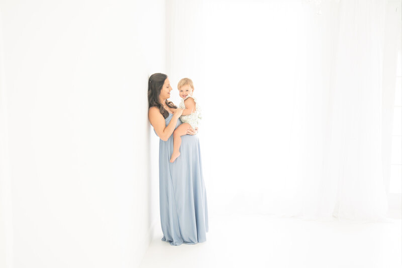 Maternity model and her daughter wearing blue in a all white photo studio