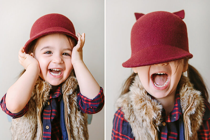 A yound girl wearng a red hat smiling and laughing in Daniele Rose Photography's portrait studio
