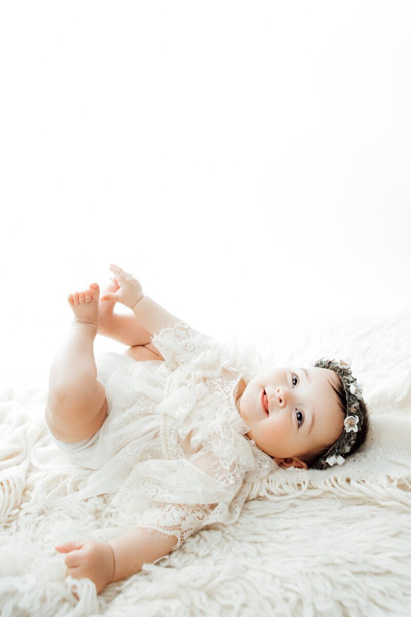 Baby laying on blanket wearing flower headband, by nj cake smash photographer