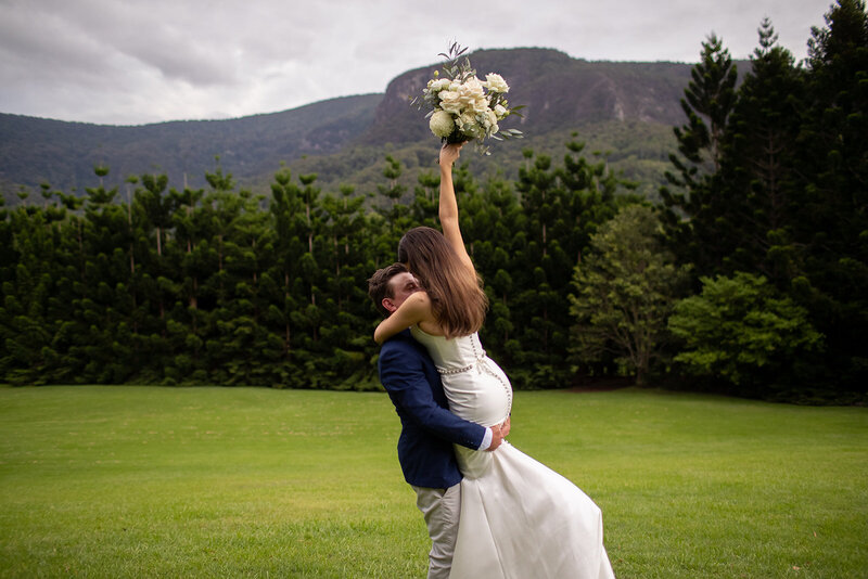 Groom lifts his Bride in the green field