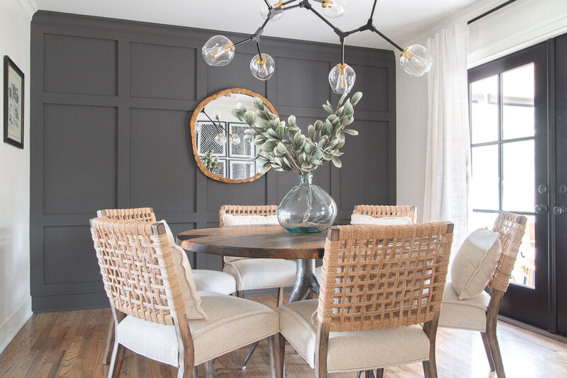 Modern transitional dining room with paneled charcoal accent wall and round table with woven back chairs designed by Lake Murray interior designer Haven + Harbor