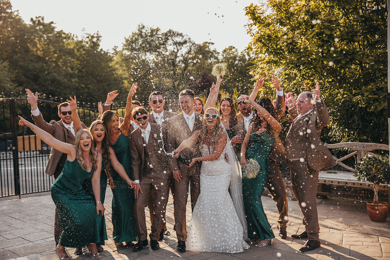 bride spraying champagne with wedding party