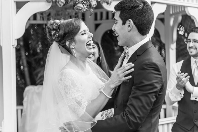 Black and white portrait of bride and groom laughing after the first kiss during ceremony