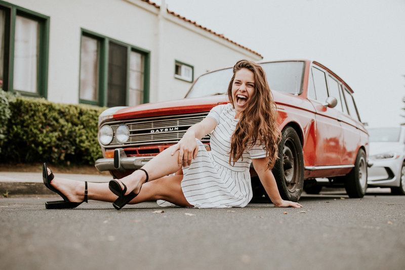 girl laughing by car