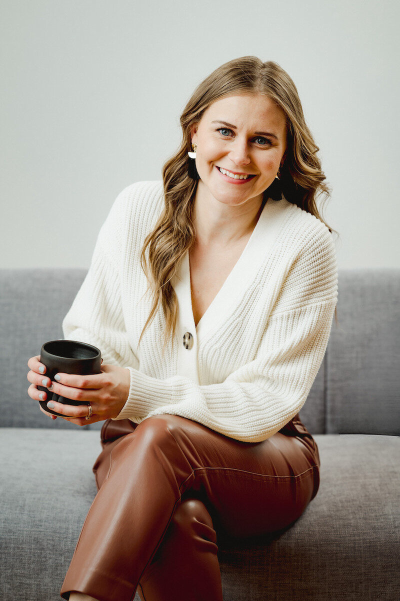 Woman sitting on a grey couch with cup of coffee