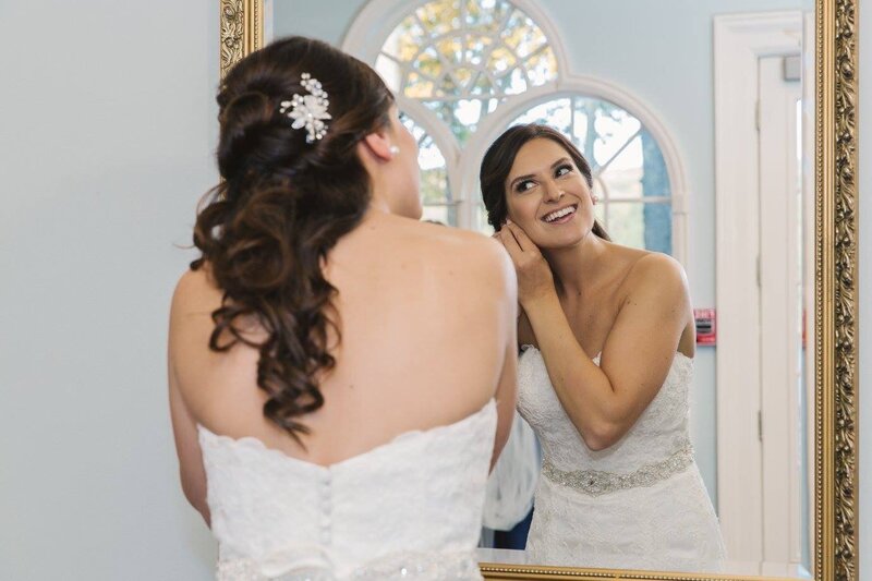 bride smiling and looking in mirror getting ready