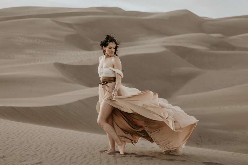 Southwest elopement photographer poses in flowy dress at the great sand dunes in colorado..