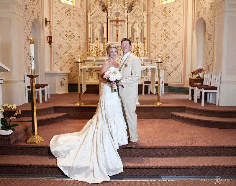 Couple stands on the altar area for their wedding portraits at Sacred Heart of Mary in Boulder