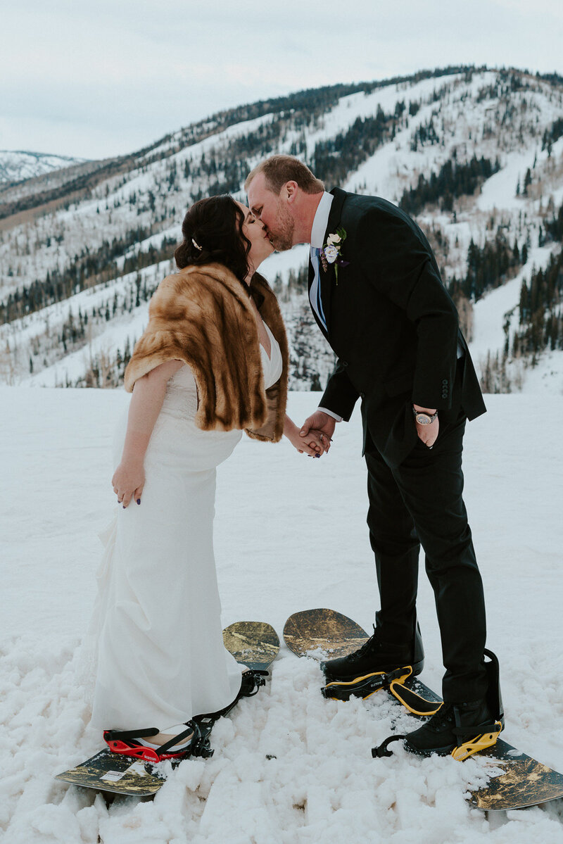 a couple in wedding attire, kisses in fron of a snow-covered Mount Rainier