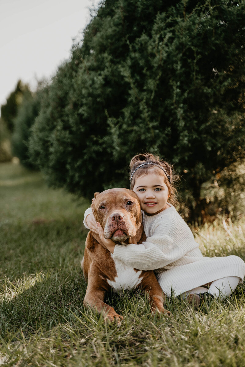 little girl sitting with her arms around her dog