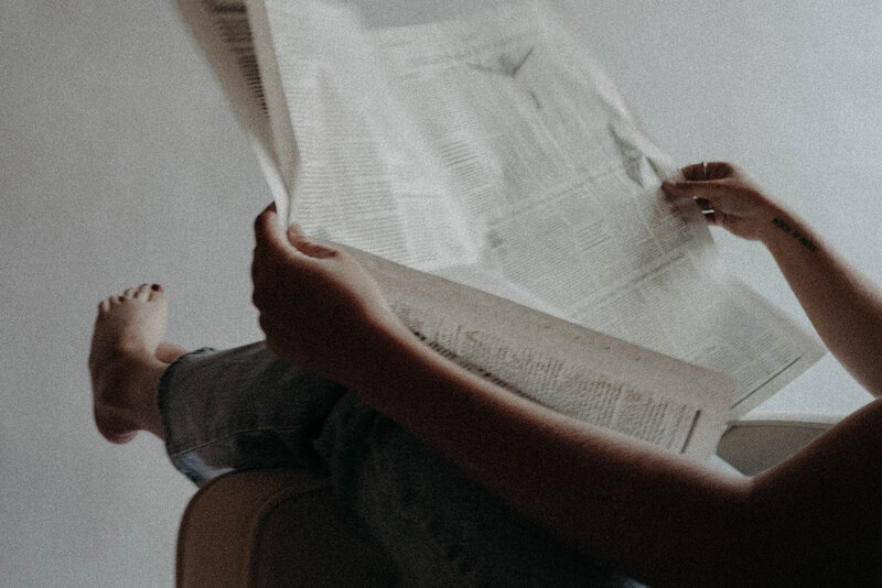 person wearing blue jeans opening newspaper