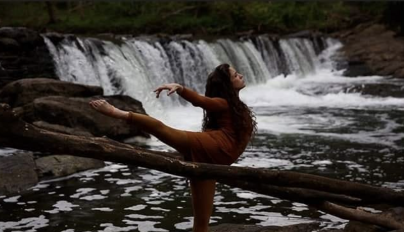 Woman dancing by waterfall