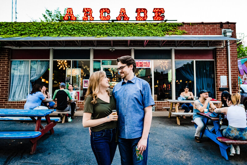 Engaged couple poses in front of a the Arcade sign at the baxter barcade in Carrboro, NC