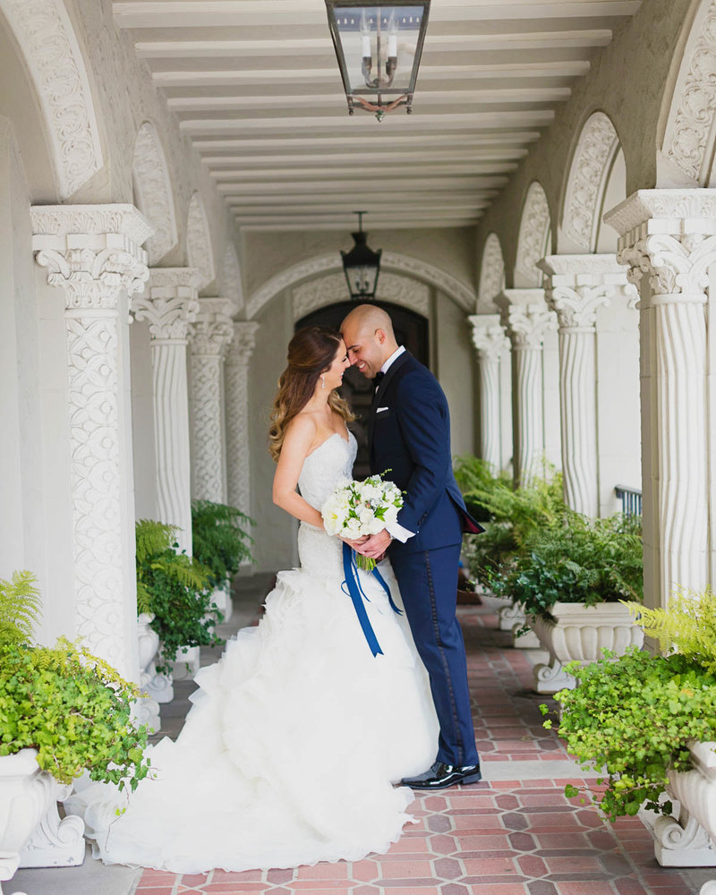 Full body portrait of Bride + Groom facing one another under a long hallway