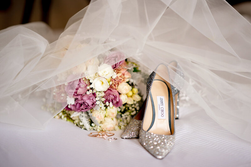 Bride's shoes and bouquet covered by a veil