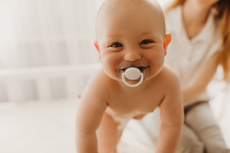 baby crawling with a pacifier in it's mouth