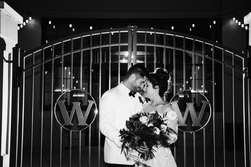 Married couple embracing in front of gates on wedding day