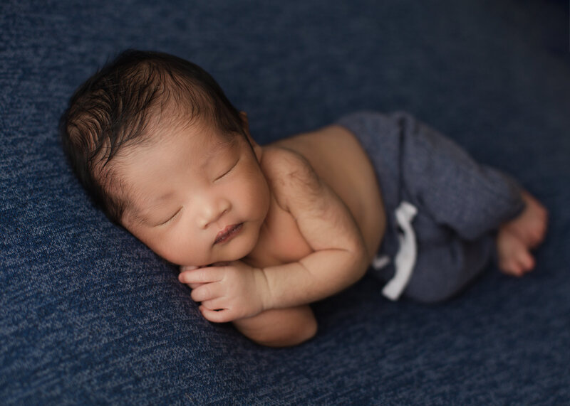 Nebworn baby boy in blue laying in his side