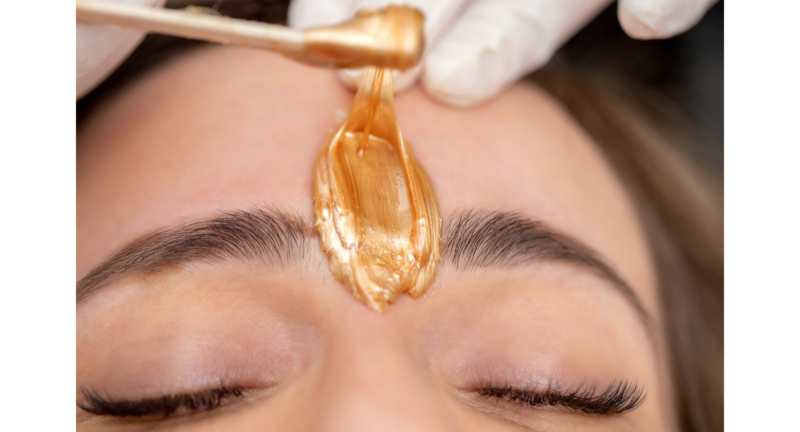 woman is having wax applied between her brows for an eyebrow wax