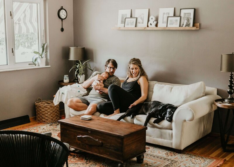 A man and woman, along with their dog, sitting on a couch. Capture this perfect moment with a Pittsburgh family photographer.