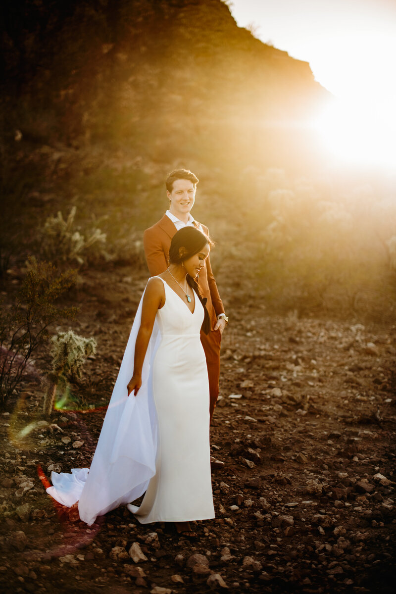 Bride and groom walking while a sun beams shine behind them