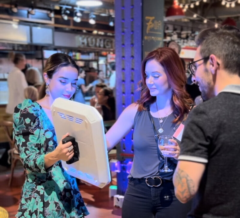 woman holding a booth on her hand while guests tye their phones on it.