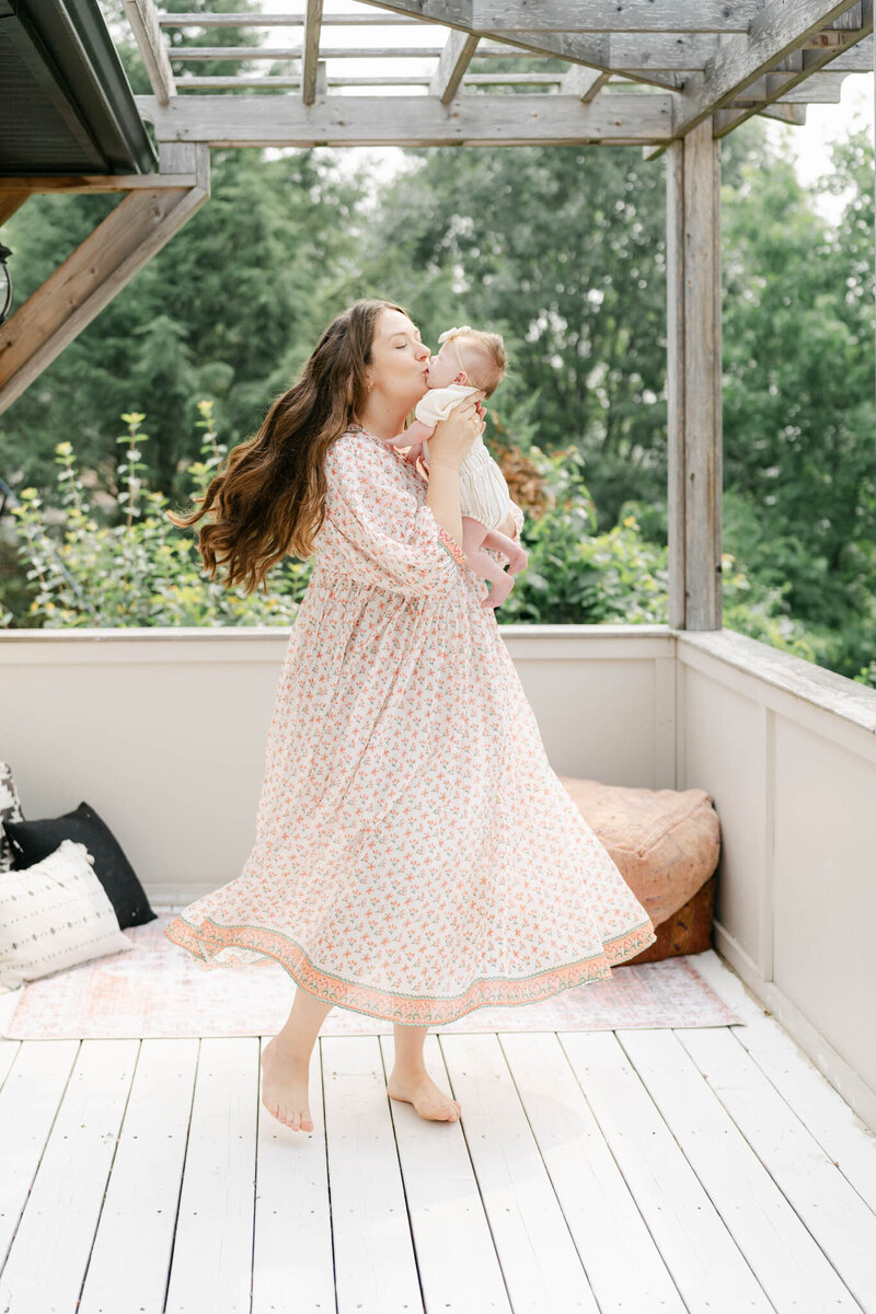 mom  holding her baby spins in a flowy dress  during a family photo session with AnneMarie Hamant