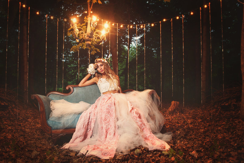Blaine Minnesota high school senior  photo of girl sitting on a couch in the woods with a chandelier