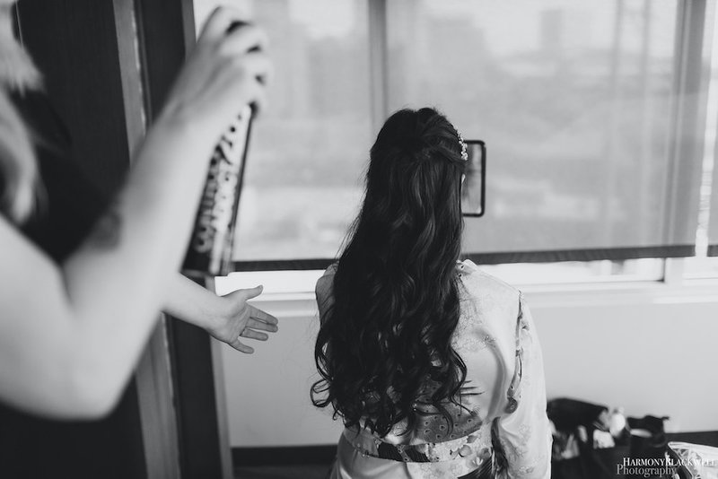 Woman sitting with back facing the camera to show hair that is being styled by a hairtsylit