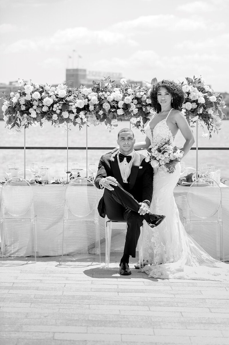 Couple poses for wedding photos in front of a flower display